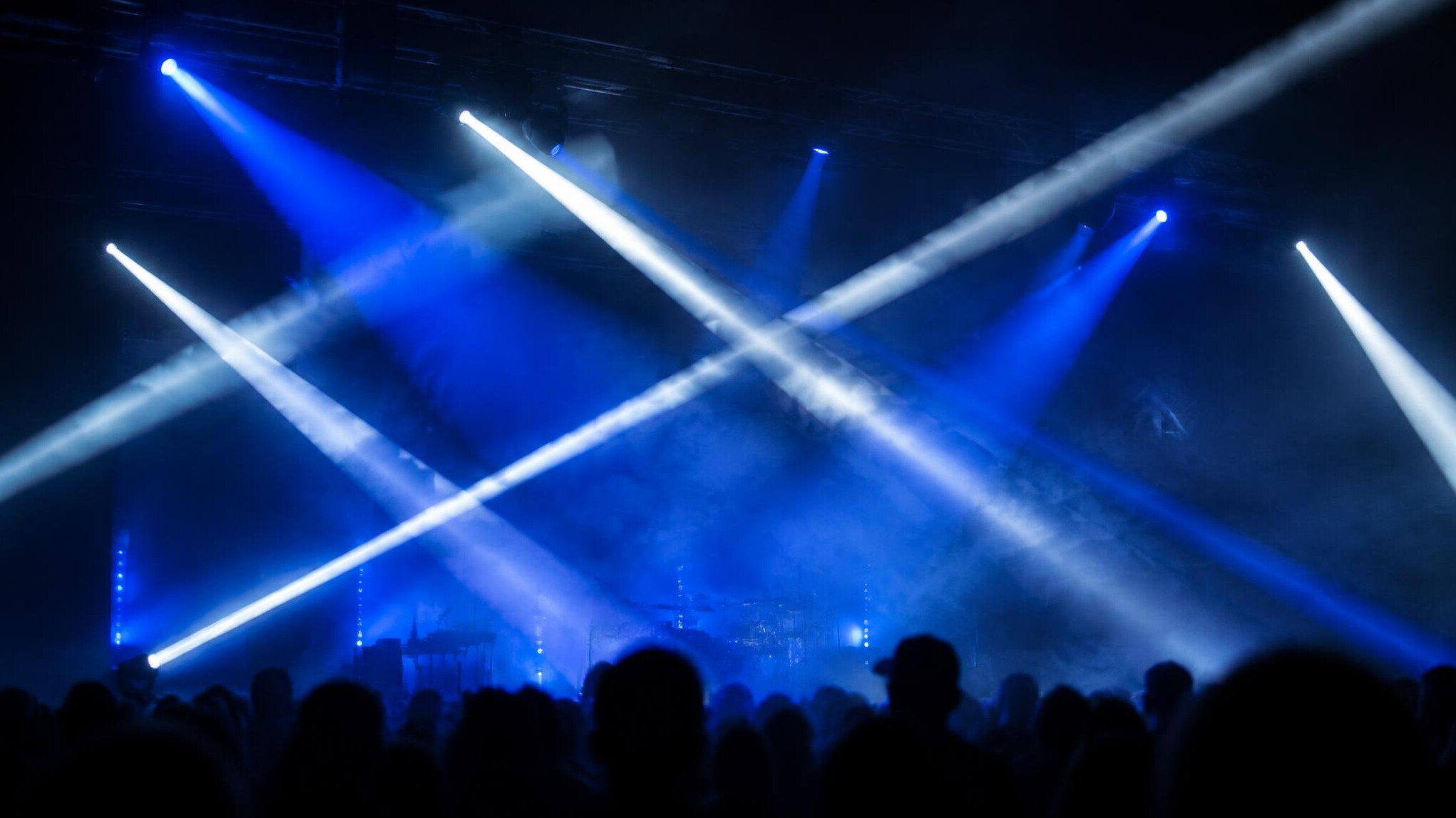Stage lights creating beams over a crowd